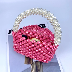 Detail van roze kralentas met wit parelhandvat en gouden metalen sluiting