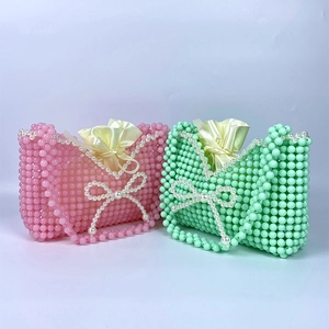 Detail of handmade beaded mini bags in pink and mint green with pearl bow and satin lining