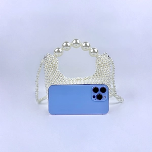 Detail van handgeweven parelhandtas met groot parelhandvat en lange schouderketting