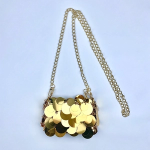 Close-up of golden round sequins on mini handbag with metallic chain strap detail