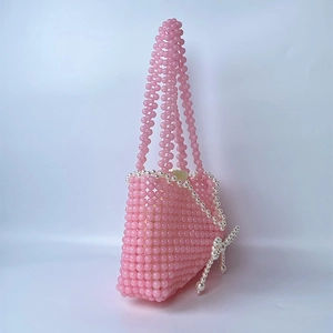 Detailed close-up of handmade pink beaded handbag with pearl bow and woven texture