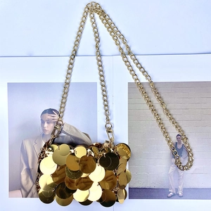 Detail of layered gold sequin mini bag with metallic chain on fashion magazine