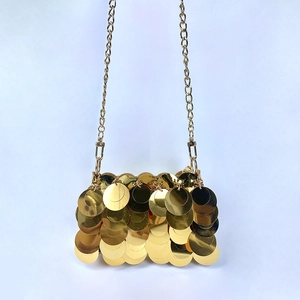 Detail of handmade gold sequin chain bag featuring reflective scale pattern on blue surface