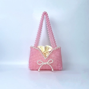Detail of pink beaded handbag with pearl bow design and golden satin drawstring lining