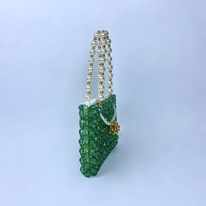 Détail d'un sac à main perlé vert fait main avec anses en perles blanches et accents dorés
