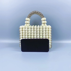 Mini pearl beaded evening bag with silver metal accents compared to a smartphone