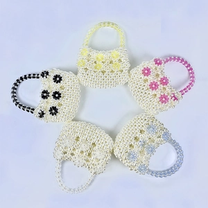 Macro detail of handmade pearl beaded bags featuring colorful acrylic flower ornaments