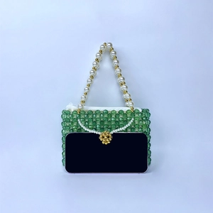 Détail d'un sac à main artisanal en perles vertes avec poignée en perles et zip