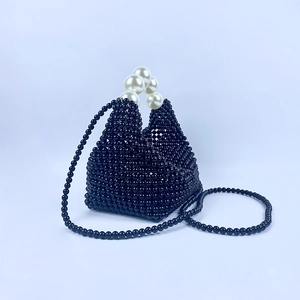 Detail van de handgeweven zwarte kralenhandtas met een groot parelhandvat ontwerp