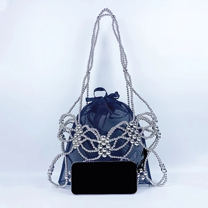 Detail of silver beaded bow shoulder bag with black mesh liner and a smartphone for scale