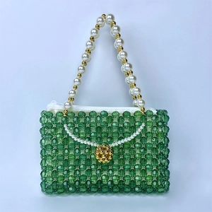 Détail d'un sac à main vert perlé à la main avec poignée en perles blanches et dorées