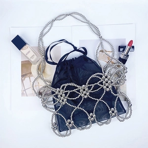 Detail of silver beaded mesh handbag with a black drawstring inner pouch on magazine