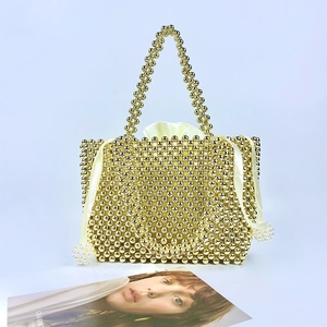 Detail of handmade gold beaded handbag with glossy metallic beads and satin drawstring liner