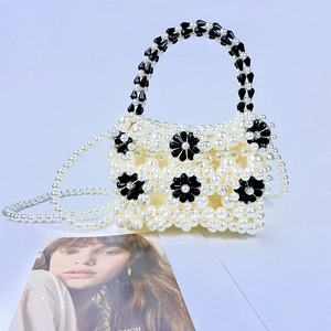 Detail of beaded handbag with white pearls and black floral patterns on the front