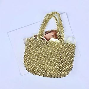 Detail of hand-woven gold beaded handbag with satin drawstring lining on a white background