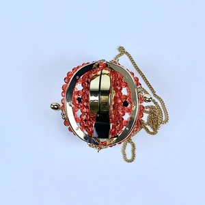 Dettaglio della cornice dorata e interno della borsa a tracolla con perline rosse