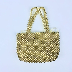 Detailed view of hand-woven gold beaded handbag with glossy finish and silk lining