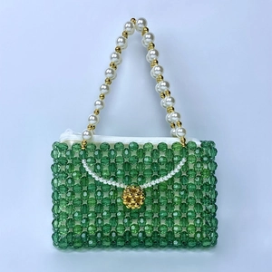 Détail du sac à main vert perlé avec des perles blanches et une fermeture dorée
