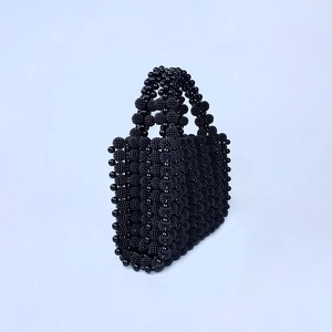 Détail d'un sac à main noir perlé avec texture tissée à la main en 3D et structure chic
