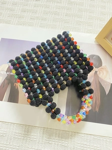 Macro shot of colorful beaded mini handbag with textured black base and rainbow beads