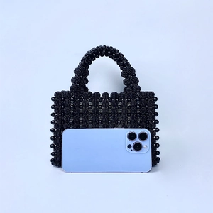 Gros plan du sac à main noir perlé avec un smartphone pour comparer la taille