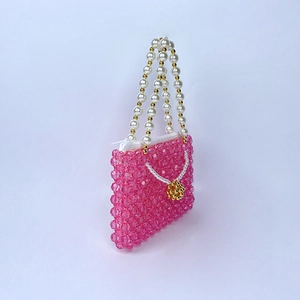 Détails d'un sac à main en perles roses avec poignée perle et accents dorés
