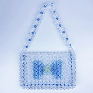 Close-up of handmade beaded bag with blue bow pattern and transparent acrylic texture
