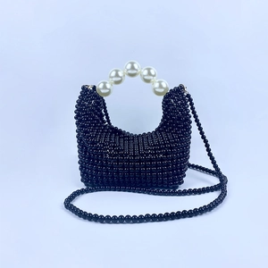Detail van handgeweven zwarte kralen handtas met grote witte parel handgreep