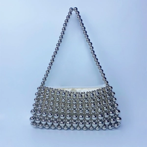 Macro shot of silver beaded handbag featuring a sleek metallic finish and white zipper closure