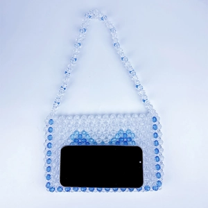 Handmade beaded bag with blue bow design shown with a smartphone for size reference