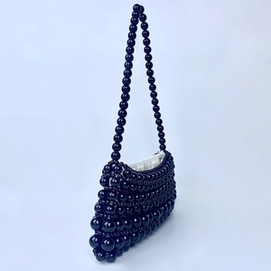 Detail view of handmade black beaded shoulder bag with glossy finish and white lining