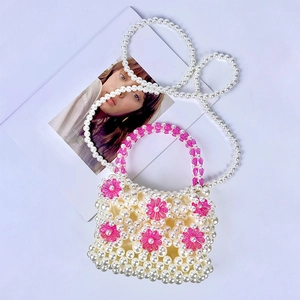 Detailed macro view of white pearl beaded bag with vibrant magenta acrylic flower accents