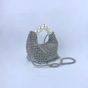 Detail van zilveren kralenhandtas met elegant groot parelhandvat voor avondkleding