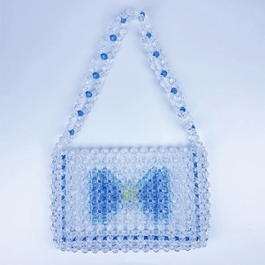 Detailed view of handmade clear beads and blue bow pattern on woven crossbody bag
