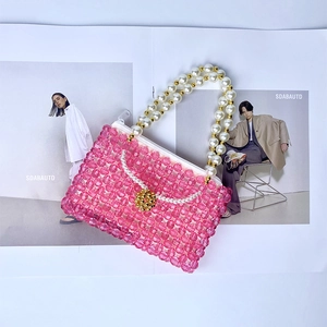 Détail d'un sac à main artisanal en perles roses avec anse perlée sur un magazine de mode