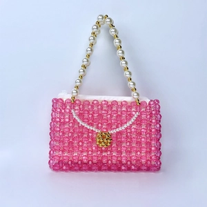 Vue détaillée du sac perlé rose avec poignée en perles et charme de perle dorée élégant