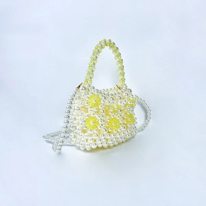 Detail of handmade pearl woven bag featuring yellow crystal flowers and beaded handle
