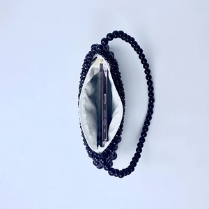 Interior view showing the capacity of a black beaded handbag with a smartphone