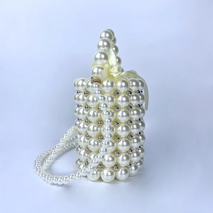Detail of beaded pearl cylinder bag featuring a silk bow and crossbody chain strap