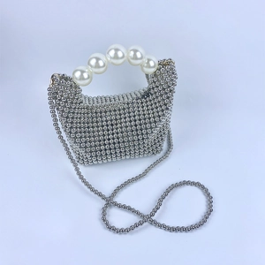 Detail van zilveren kralentas met witte parel handvat en een metalen schouderketting