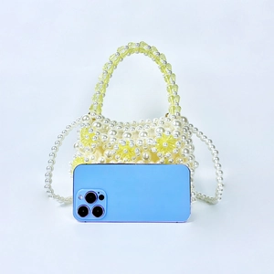 Macro shot of handmade pearl beaded bag with yellow acrylic floral accents and mobile phone