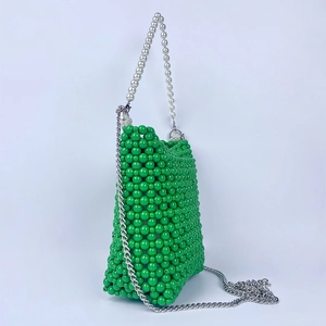 Detail of bright green beaded bucket bag with pearl handle and silver chain strap
