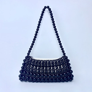 Detail of the handcrafted black beaded shoulder bag featuring glossy circular pearls texture