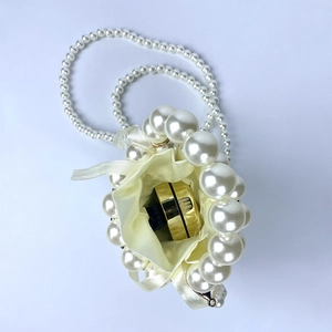 Detail view of handmade pearl mini bag with beige satin lining and drawstring closure