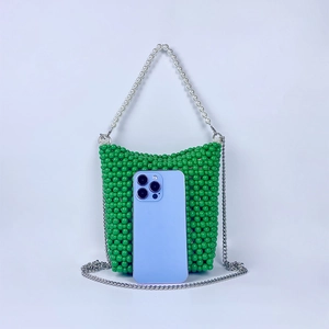Macro shot of green beaded bucket bag with pearl handle and phone for size reference