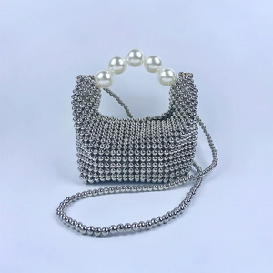 Detail van zilveren geweven minitas met groot parelhandvat en lange ketting schouderriem