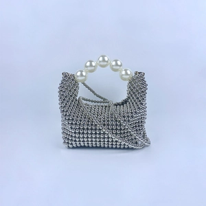 Detail van zilveren kralenhandtas met grote witte parelhendel en fijne schouderketting