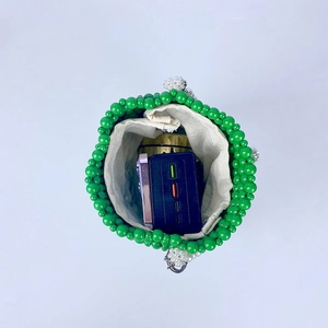 Detail view of green beaded bucket bag showing white inner pouch and interior space