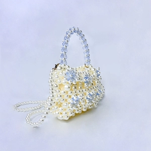 Detail of beaded pearl handbag with blue acrylic flowers and woven shoulder strap