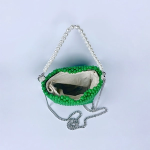 Detail of green handmade beaded bucket bag with white pearl handle and silver chain strap